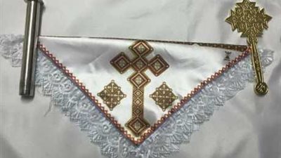 لماذا يمسك شماس لفافه مثلثة أثناء التناول و بها صليب ناحية اليمين وشمعة ناحية اليسار ؟؟